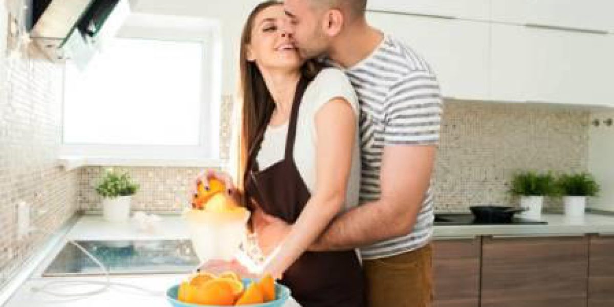 Portrait of loving young couple cuddling tenderly while cooking breakfast in kitchen on sunny morning